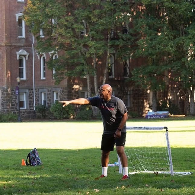 Dr. Miles K. Davis engaging with students on a university campus lawn